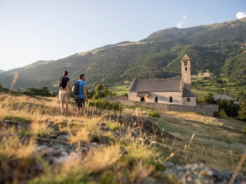 Wanderpaar bei der historischen Kirche im Vinschgau